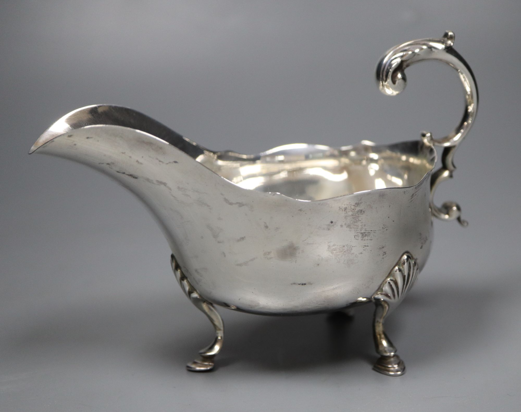 A George V silver sauceboat, Sheffield, 1917, 60z and a plated stand.